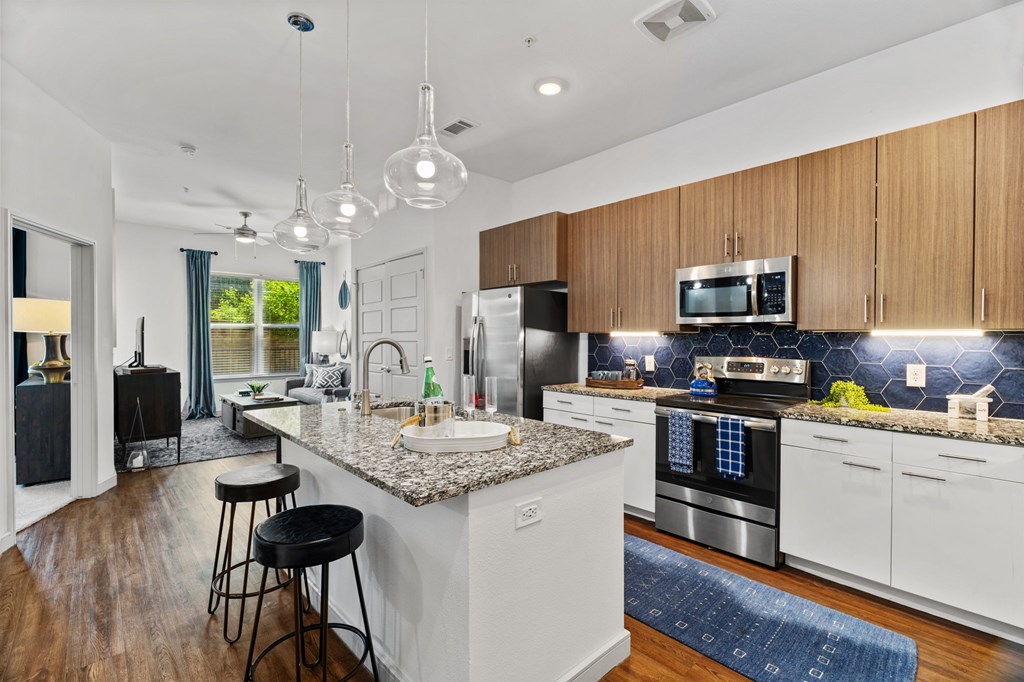A modern kitchen with a granite countertop and stainless steel appliances.