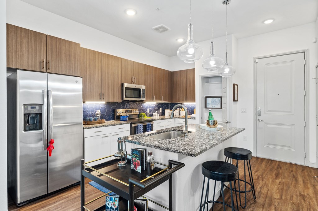 A kitchen with a granite countertop and a stainless steel refrigerator.