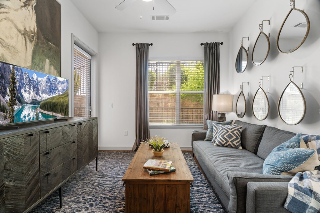 A living room with a grey couch, a wooden coffee table, and a large painting on the wall.