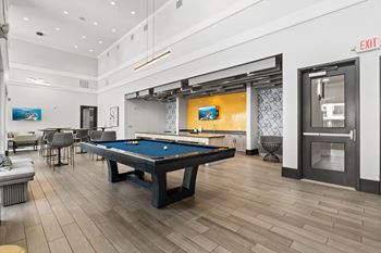 A pool table is in the middle of a room with a door to the right.