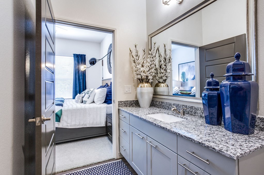 a bathroom with a sink and a mirror and a door to a bedroom