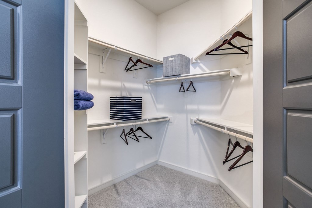 a walk in closet with white walls and shelves and a blue door