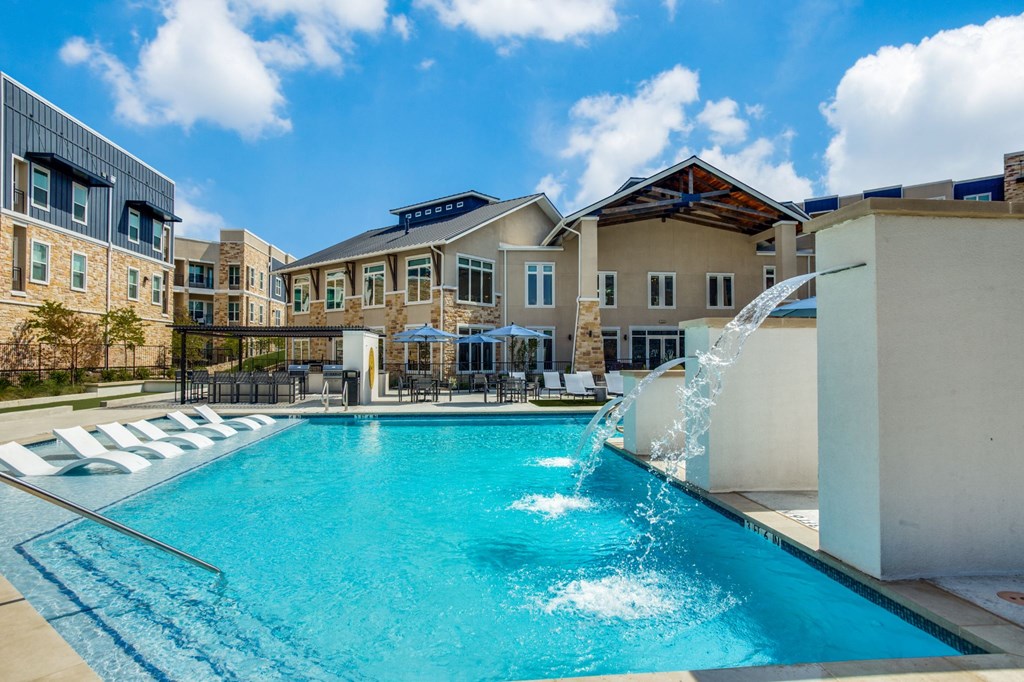 a swimming pool with a water fountain in front of apartments