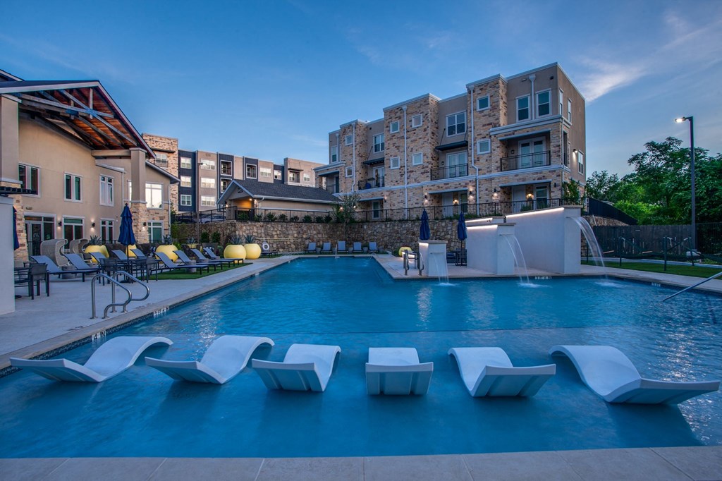 a swimming pool with lounge chairs in front of a building