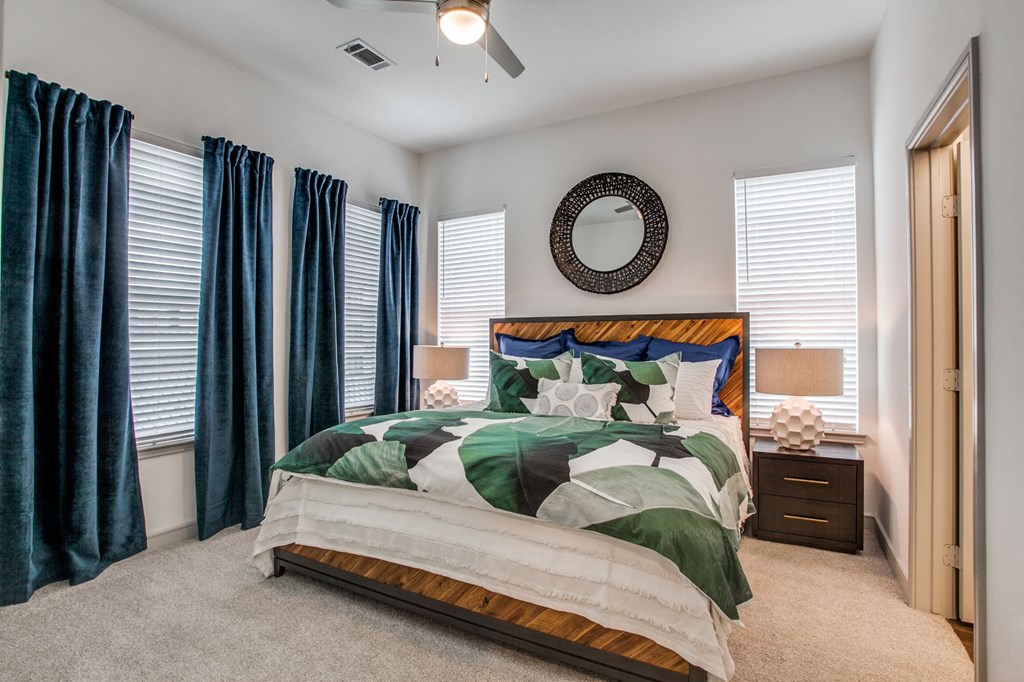 a bedroom with a bed with green and white bedding and blue curtains