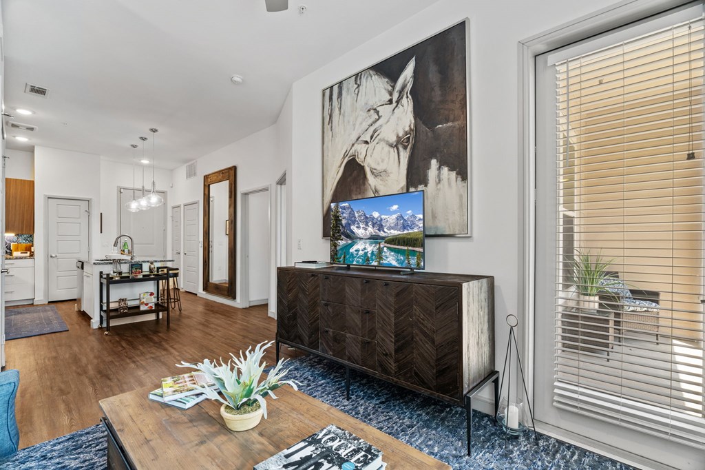 A living room with a large painting on the wall and a wooden coffee table in the center.