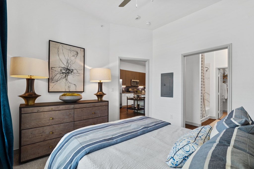 A bedroom with a bed, dresser, and two lamps.