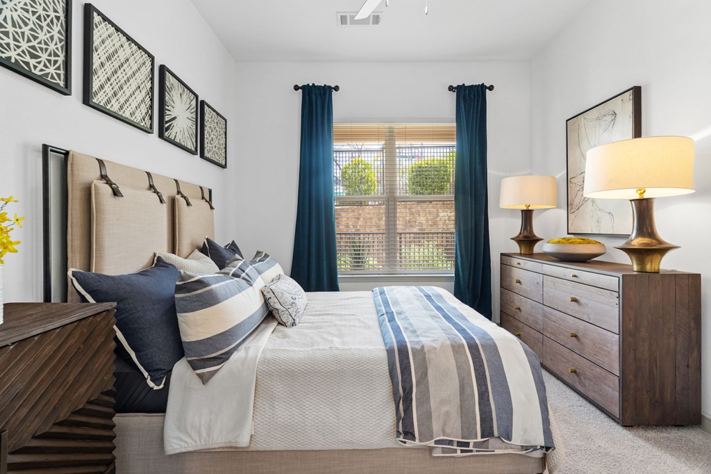 A bedroom with a large bed, two lamps, and a window with curtains.