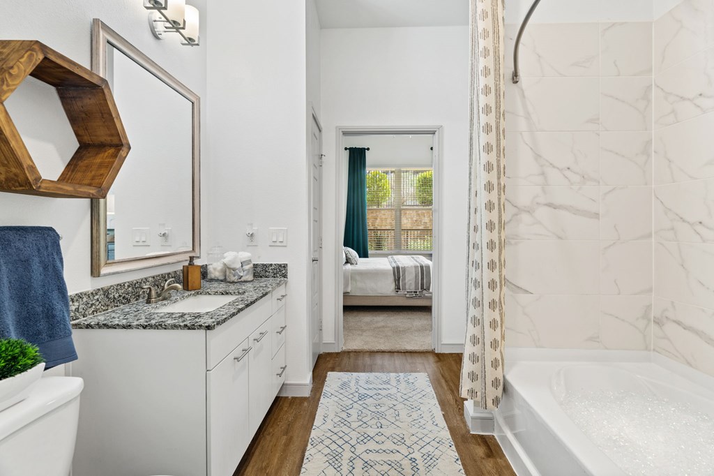 A bathroom with a white tub and a marble wall.