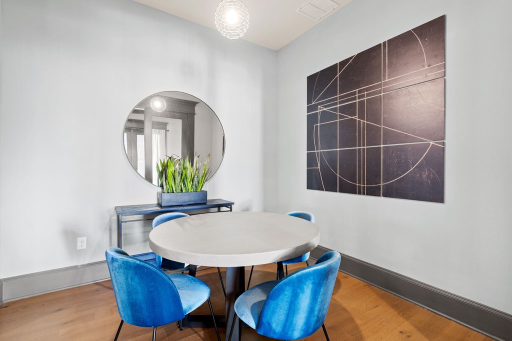 a dining room with blue chairs and a white table and a mirror