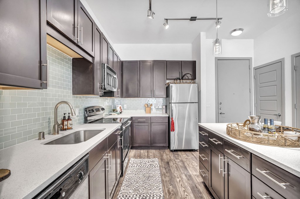 a kitchen with white countertops and dark wood cabinets