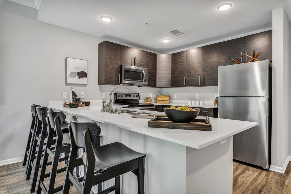 a kitchen with a large island with bar stools and a stainless steel refrigerator