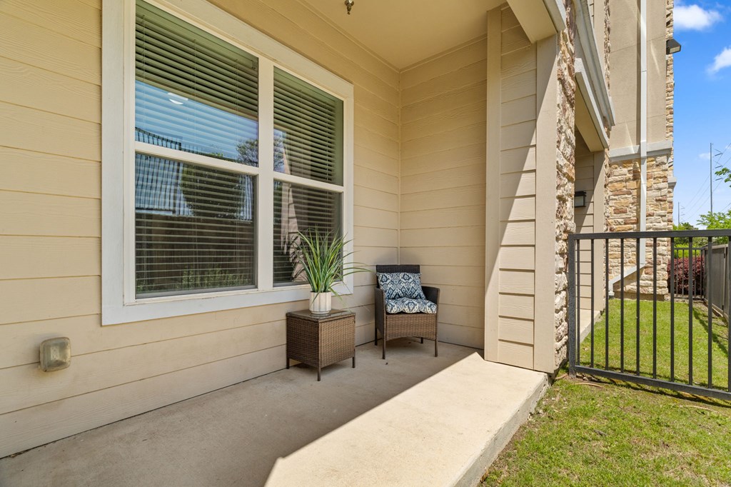 A patio with a chair and a table with a potted plant on it.