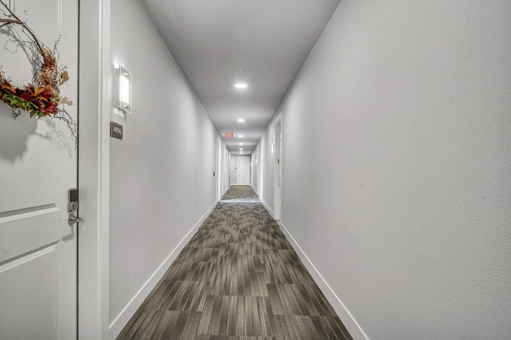 a long corridor with white walls and wood flooring and white doors
