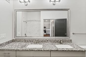 A bathroom with a large mirror above a counter with two sinks.