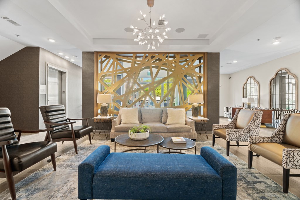 A living room with a blue ottoman and a large wooden artwork on the wall.