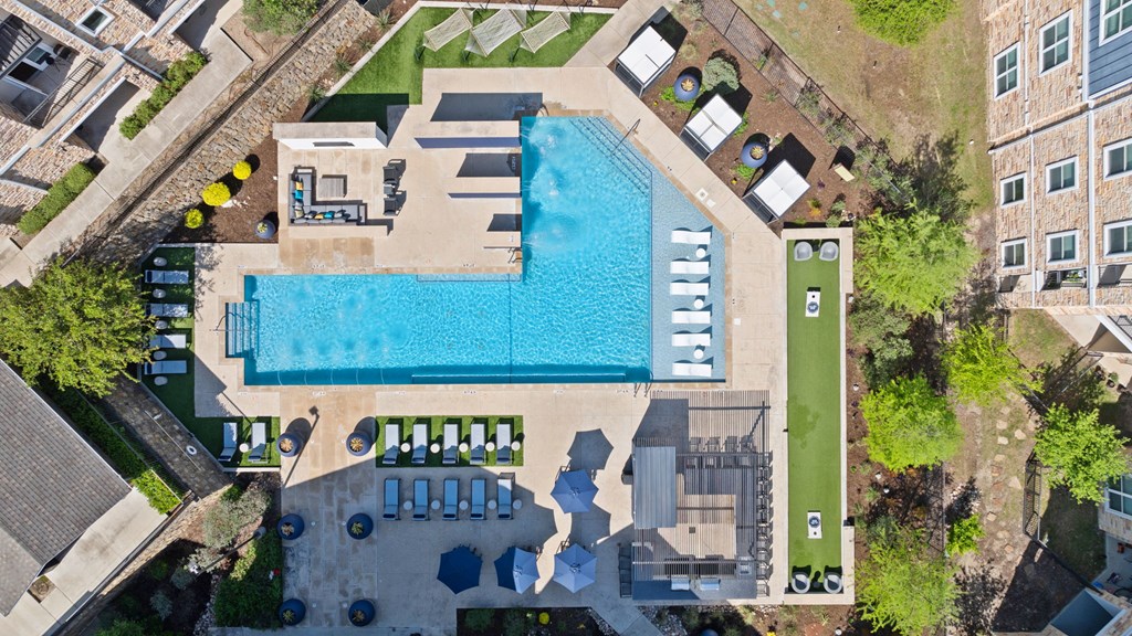An aerial view of a swimming pool surrounded by lounge chairs and umbrellas.
