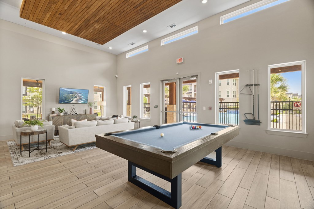 A pool table is in the middle of a room with a couch and a chair.