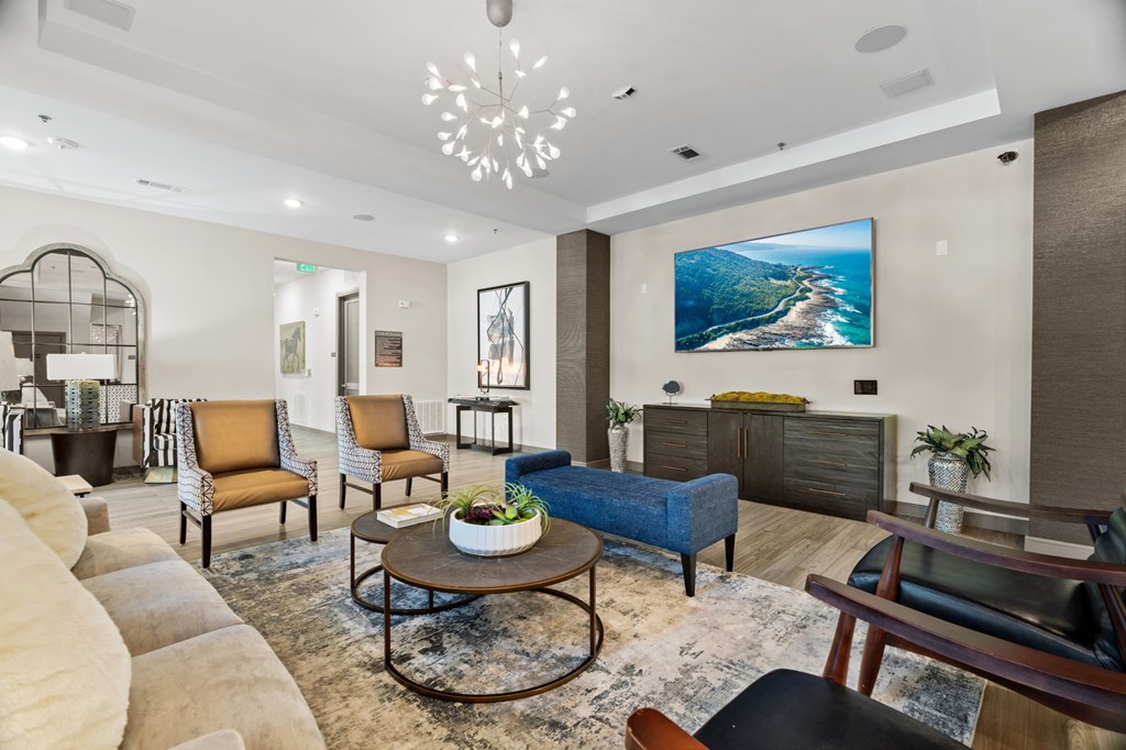A living room with a large painting on the wall and a coffee table in the center.