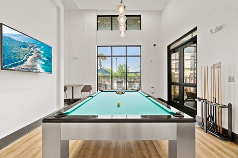 A pool table in a room with a view of the ocean.