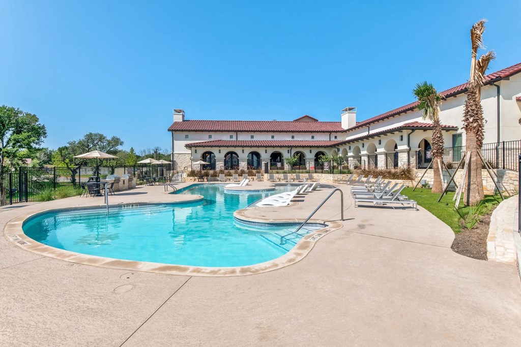 a resort style pool with chairs around it and a building in the background