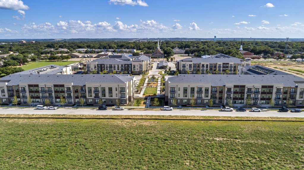 an aerial view of an apartment complex with cars parked in a parking lot