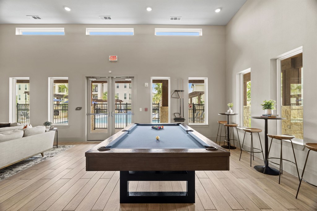 A pool table is in the middle of a room with a couch and a chair.