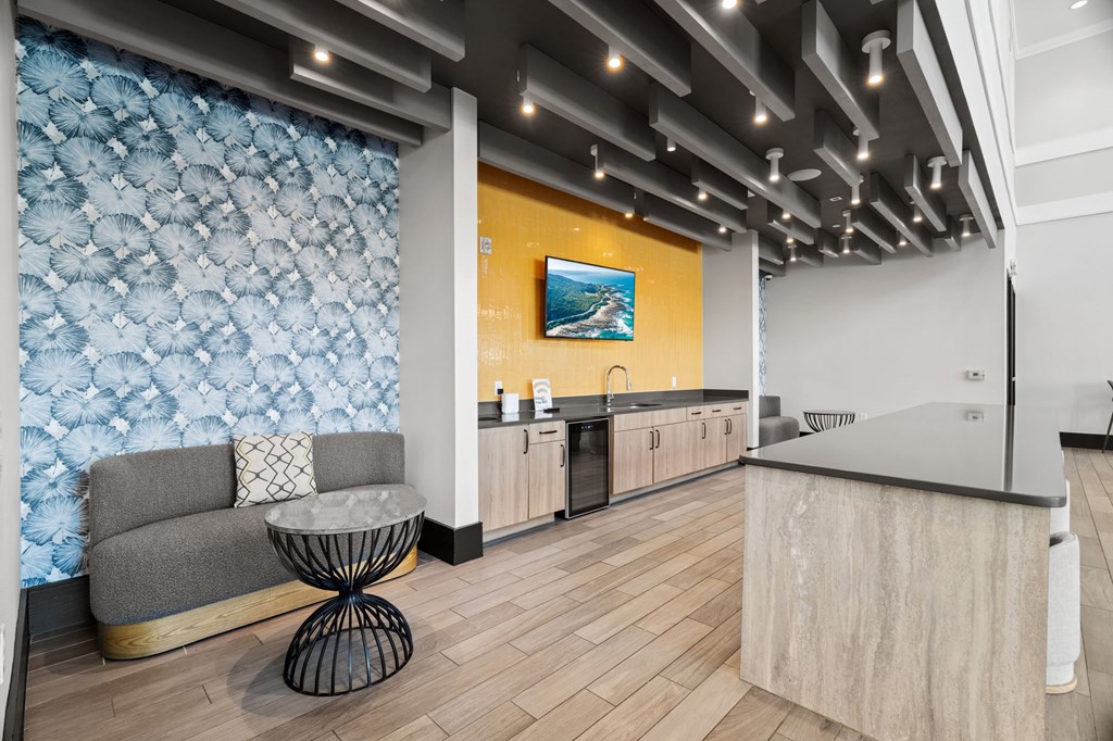 A modern kitchen with a grey sofa and a wooden floor.