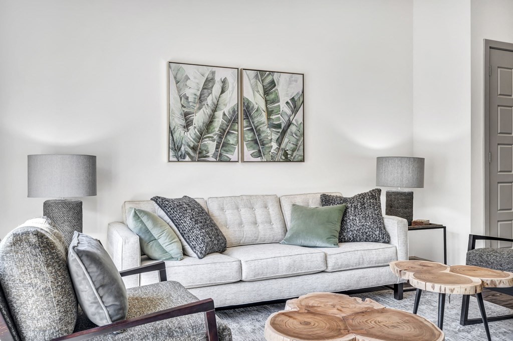 a living room with white walls and a white couch with green pillows