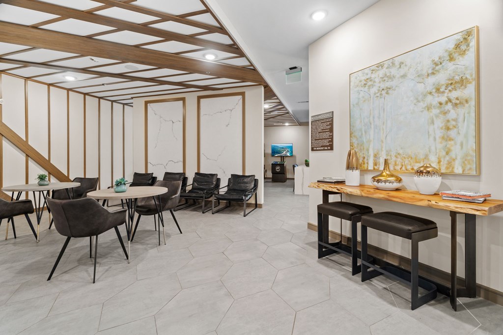 A room with a large painting on the wall and a long table with chairs.