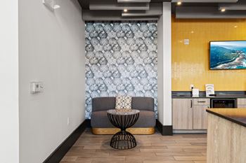 A modern kitchen with a yellow wall and a grey chair.