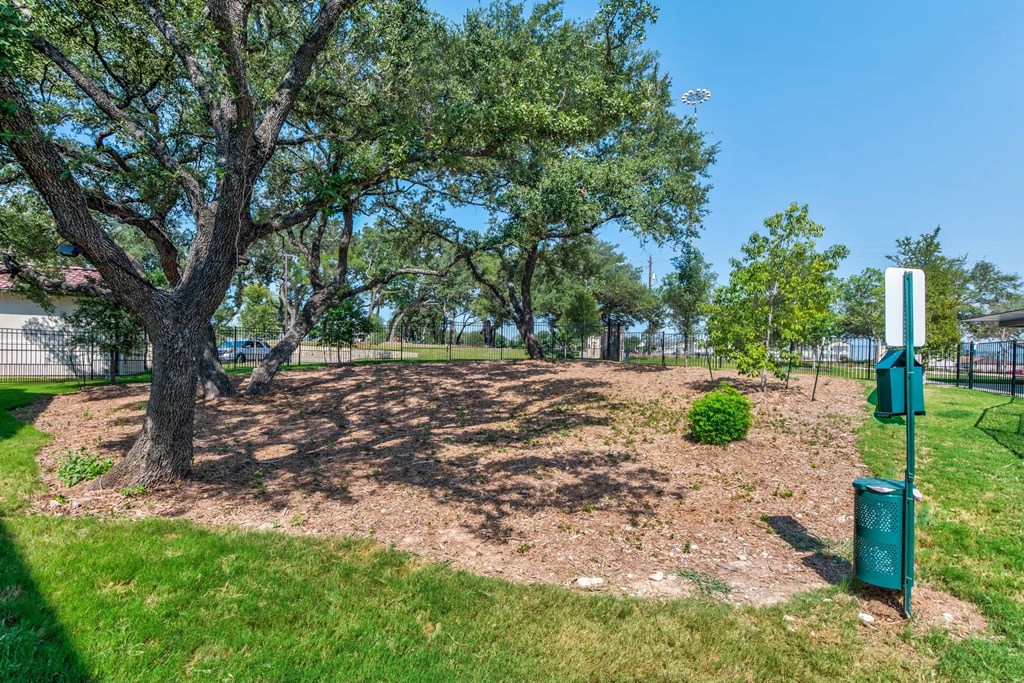 a park with a tree and a sign in the grass