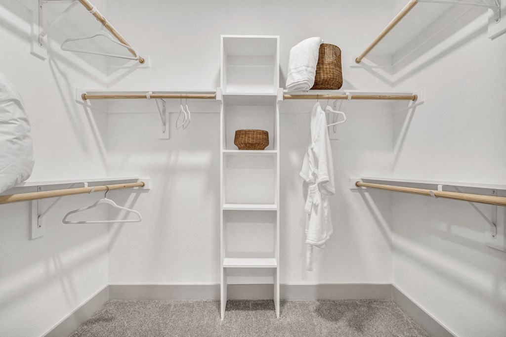a walk in closet with white shelves and robes and a ladder