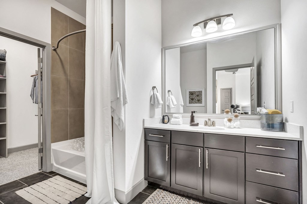 a bathroom with dark cabinets and a large mirror