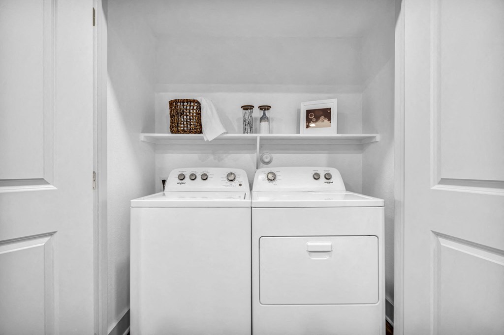 a white laundry room with two washes and a dryer