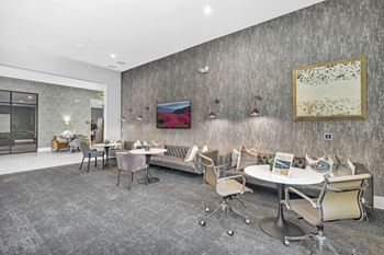 a seating area with tables and chairs in front of a wall with a painting