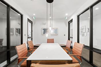 A conference room with a long table surrounded by orange chairs.