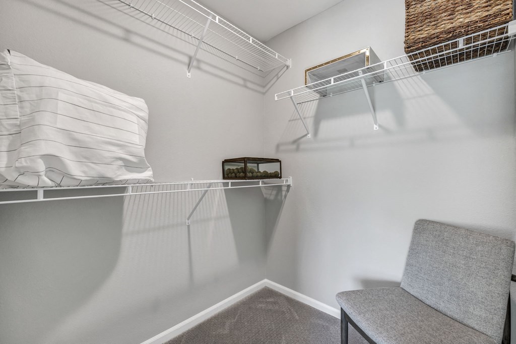 a spacious closet with a chair and a shelf with a pillow