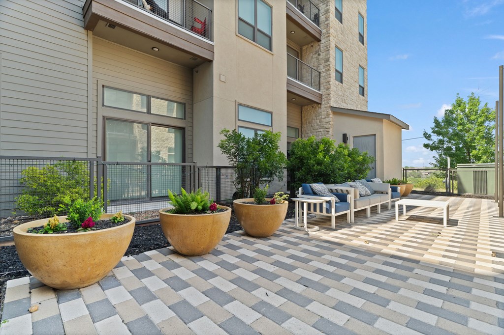 A patio with a checkered floor and three large planters.