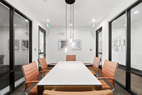 A conference room with a long table surrounded by orange chairs.