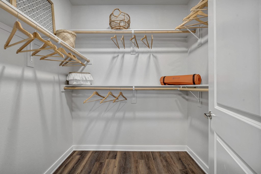 a walk in closet with white walls and shelves and a white closet door