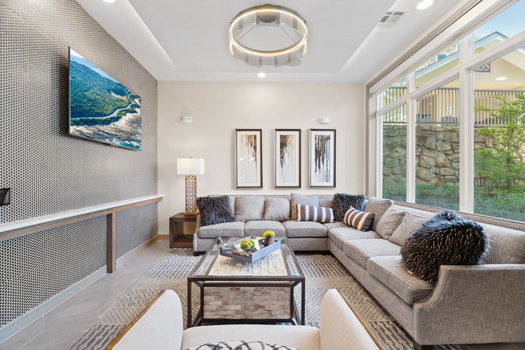 A modern living room with a grey couch, a coffee table, and a large painting on the wall.