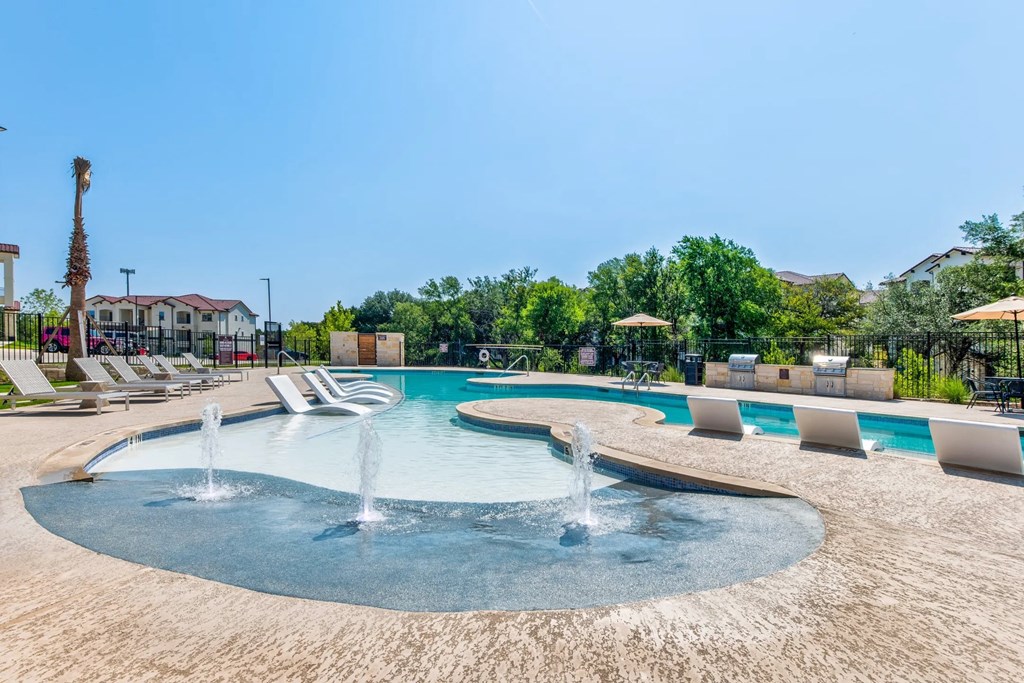 a large swimming pool with chairs and water fountains