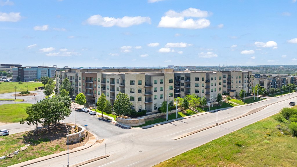 A road with a sidewalk and a grassy area with a tree.