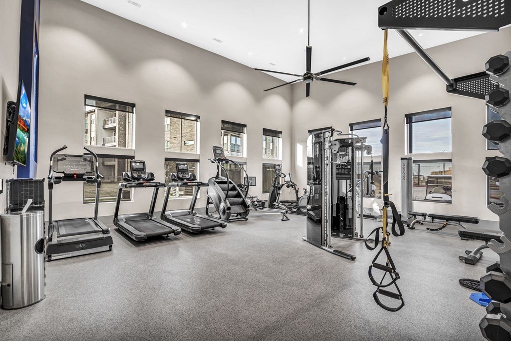 a gym with cardio equipment and windows in a building