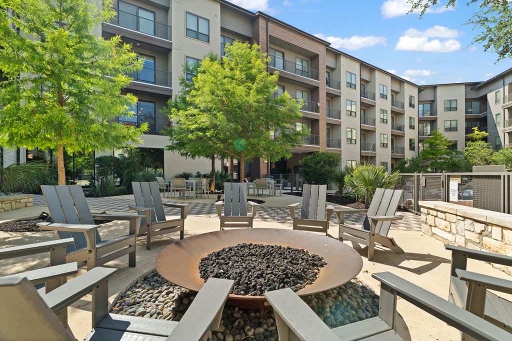 A large circular fire pit sits in the middle of a patio surrounded by chairs.