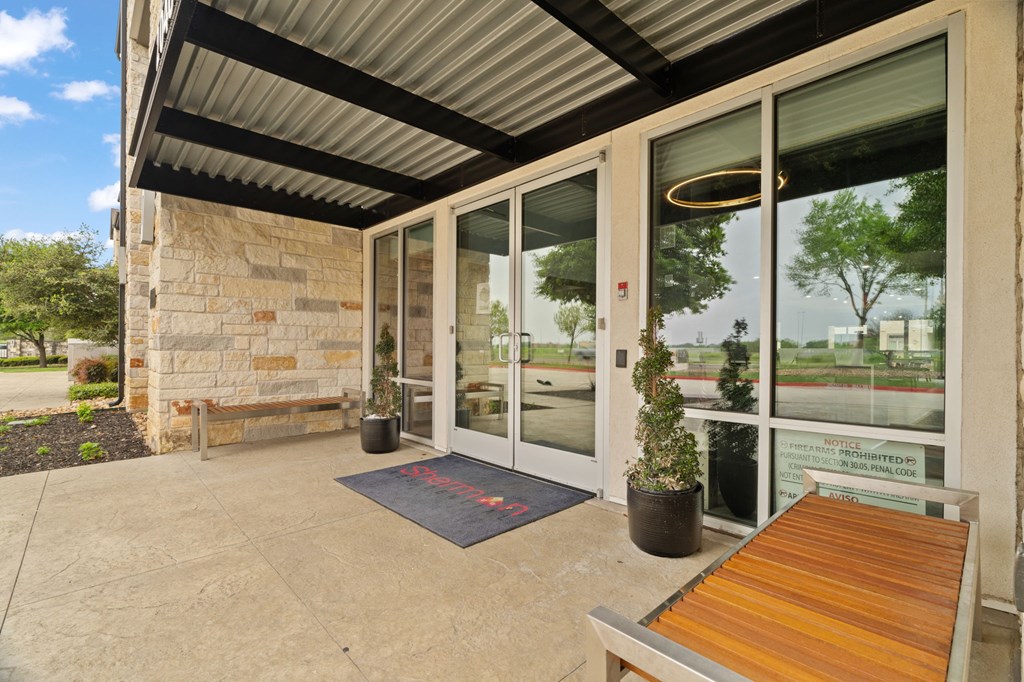 A building entrance with a bench and a plant.