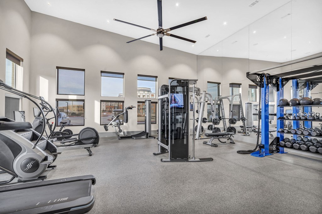 a gym with weights and cardio machines and a ceiling fan