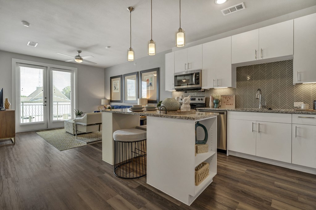 a kitchen with an island and a living room with a balcony