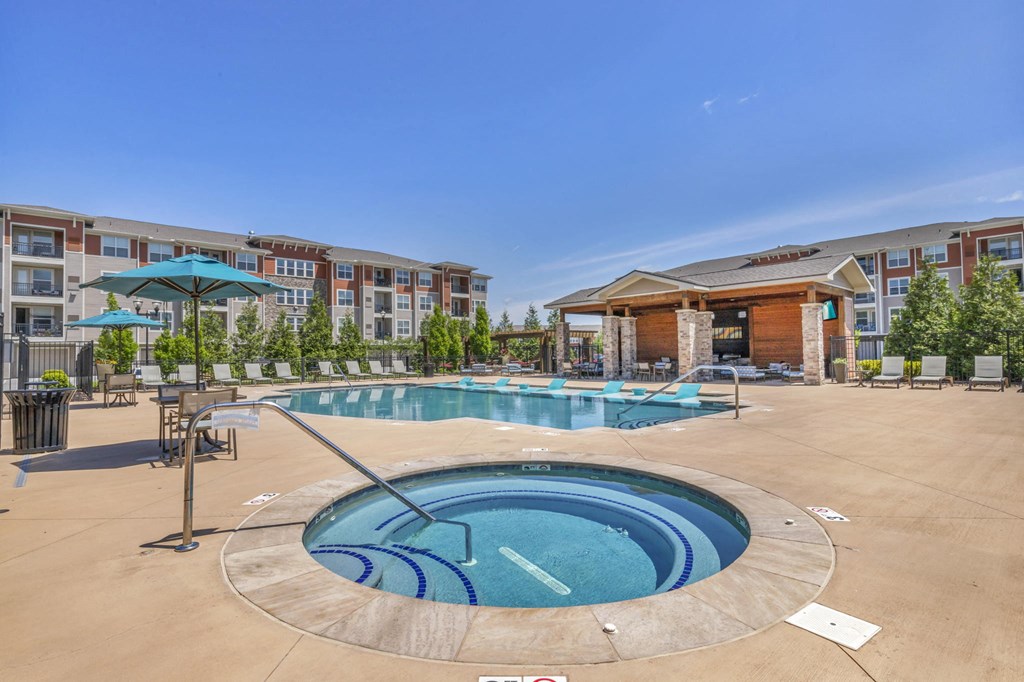 a swimming pool with a hot tub in front of an apartment building